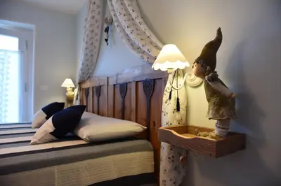 a bedroom with a bed with a doll next to a lamp at B&B Magiré in Tesero