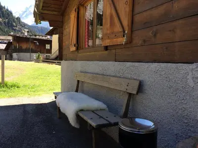 a bench with a white blanket on it next to a building at Garnì Serena in Canazei