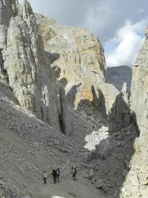 three people walking on a rocky mountain trail at Gasthof Specker in Obereggen