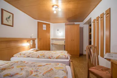 a hotel room with two beds and a chair at Gasthof Specker in Obereggen