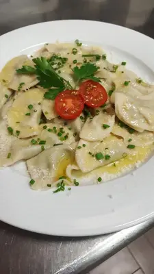 a white plate of food with tomatoes and parsley at Gasthof Specker in Obereggen