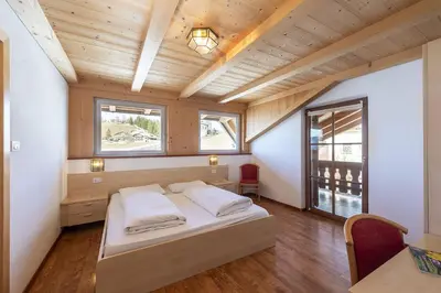 a bedroom with a bed and a wooden ceiling at Gasthof Specker in Obereggen