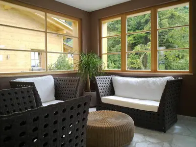 a porch with two chairs and a table and windows at Residence Comploj in Santa Cristina in Val Gardena