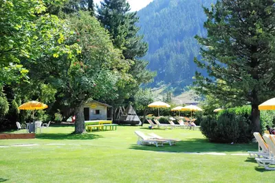 a group of chairs and umbrellas in a park at Residence Comploj in Santa Cristina in Val Gardena
