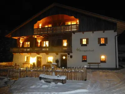 a large building in the snow at night at Bruggerhof Prags in Braies