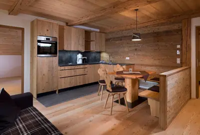 a kitchen with wooden cabinets and a table and chairs at Bruggerhof Prags in Braies