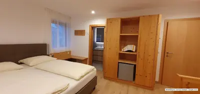 a bedroom with a bed and a wooden cabinet at B&B Haus Grüner in Valdaora