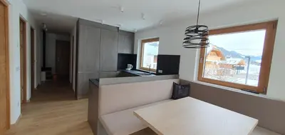 a living room with a table and a kitchen at B&B Haus Grüner in Valdaora