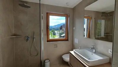 a bathroom with a sink and a toilet and a window at B&B Haus Grüner in Valdaora