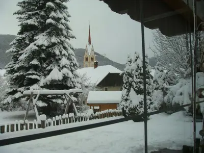 a church with a christmas tree in the snow at B&B Haus Grüner in Valdaora