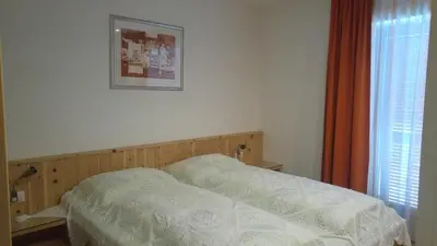a bed in a bedroom with a picture on the wall at B&B Haus Grüner in Valdaora
