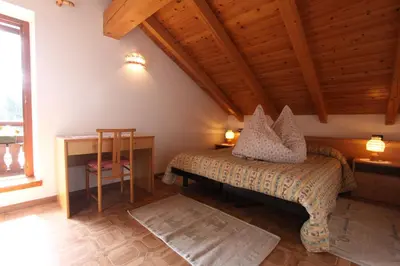 a bedroom with a bed and a desk and a window at Agritur Chelodi in Cavalese
