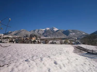 a snow covered field with mountains in the background at Agritur Chelodi in Cavalese