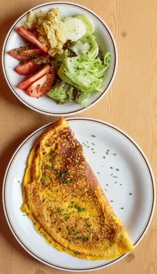two plates of food with a omelet and a salad at Gasthaus Furlhütte in Vipiteno