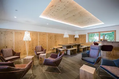 a waiting room with wooden walls and chairs and a table at Paloria Apartments & Sport in Lagundo