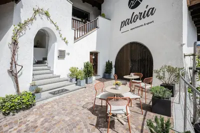 a patio with tables and chairs in front of a building at Paloria Apartments & Sport in Lagundo