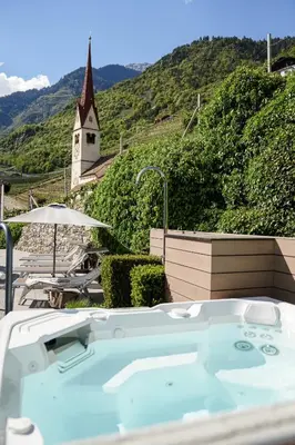 a jacuzzi tub with a church in the background at Paloria Apartments & Sport in Lagundo