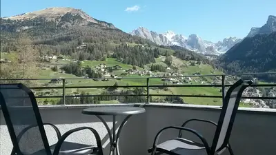 a table and chairs on a balcony with a view of a mountain at Arpa Chalet in Santa Cristina in Val Gardena