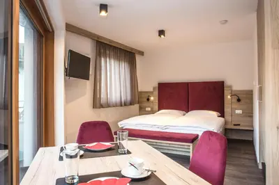 a hotel room with a bed and a table and chairs at Arpa Chalet in Santa Cristina in Val Gardena