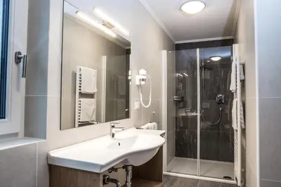 a white bathroom with a sink and a shower at Arpa Chalet in Santa Cristina in Val Gardena