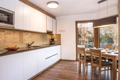 a kitchen with white cabinets and a table with chairs at Arpa Chalet in Santa Cristina in Val Gardena