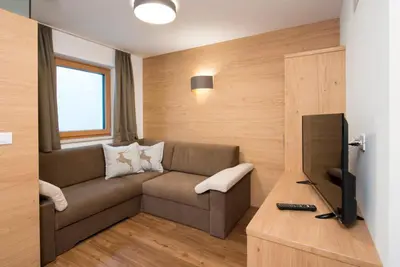 a living room with a couch and a television at Arpa Chalet in Santa Cristina in Val Gardena