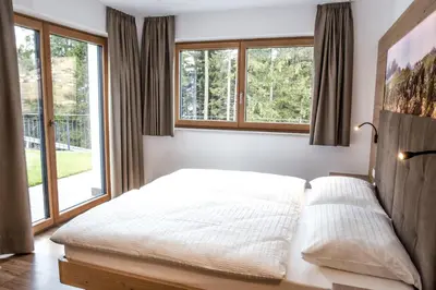 a bedroom with a bed and two windows at Arpa Chalet in Santa Cristina in Val Gardena