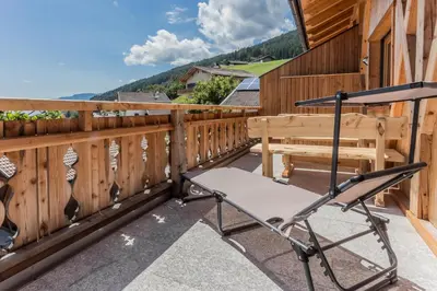 a patio with a chair and a bench on a fence at Wegscheiderhof in Feldthurns