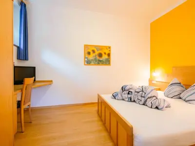 a bedroom with two beds and a desk and a television at Apartment Wolfsthurn by Interhome in Andrian