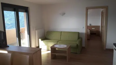 a living room with a green couch and a table at Residence Vellauerhof in Lagundo