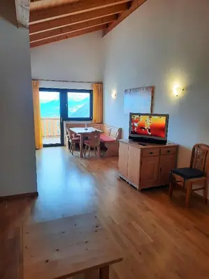 a living room with a television and a table and chairs at Residence Vellauerhof in Lagundo