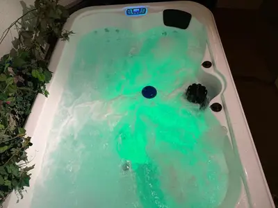 a bath tub filled with blue water with a teddy bear at Hotel Marianna in Rocca Pietore