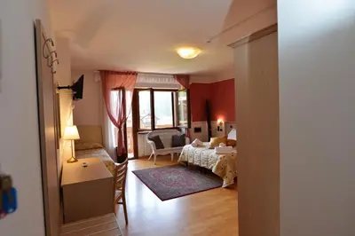 a bedroom with a bed and a living room at Hotel Marianna in Rocca Pietore