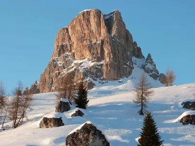 a large rocky mountain in the snow with trees at Cesa Fossal in Colle Santa Lucia