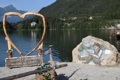 a statue of a man sitting on a rock next to a lake at Cesa Fossal in Colle Santa Lucia