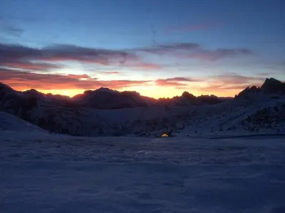 a sunset over a snow covered mountain range at Cesa Fossal in Colle Santa Lucia