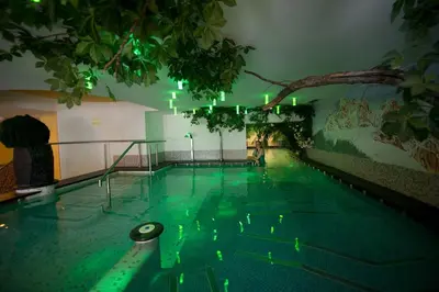 a swimming pool with green lights in a building at Family & Wellness Hotel Fontana in Vigo di Fassa