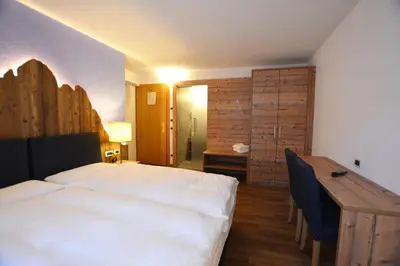 a bedroom with a bed and a desk and a table at Hotel Nès Crépes in Pozza di Fassa