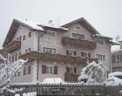 a building with a sign on it in the snow at Hotel Nès Crépes in Pozza di Fassa