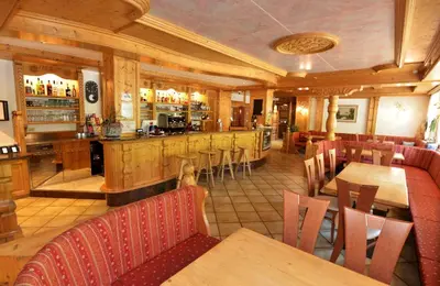a restaurant with a bar and tables and chairs at Wellness Hotel Dolomia in Soraga