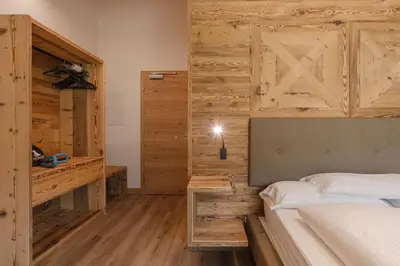 a bedroom with a bed and a wooden wall at Wellness Hotel Dolomia in Soraga