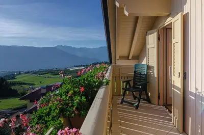 a balcony of a house with a chair and flowers at Agritur Cristina in Coredo