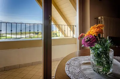 a vase of flowers sitting on a table with a window at Agritur Cristina in Coredo