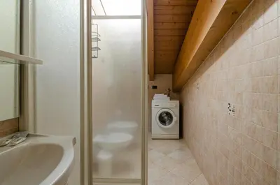 a bathroom with a sink and a washing machine at Agritur Cristina in Coredo