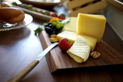 a wooden cutting board with cheese and strawberries and a knife at Untermairhof B&B Christine in Lagundo