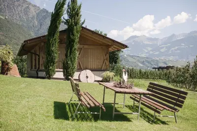 a table and two chairs in a yard with a cabin at Untermairhof B&B Christine in Lagundo