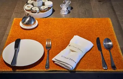 a table with utensils on a orange place mat at Ciasa Verena in Corvara in Badia