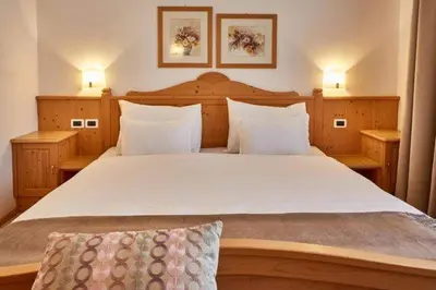 a bedroom with a large white bed with two lamps at Ciasa Verena in Corvara in Badia