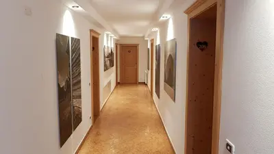 a long hallway with paintings on the walls at Ciasa Verena in Corvara in Badia
