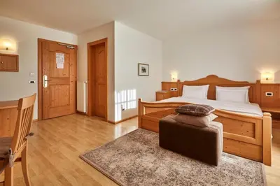 a bedroom with a bed with a ottoman in it at Ciasa Verena in Corvara in Badia